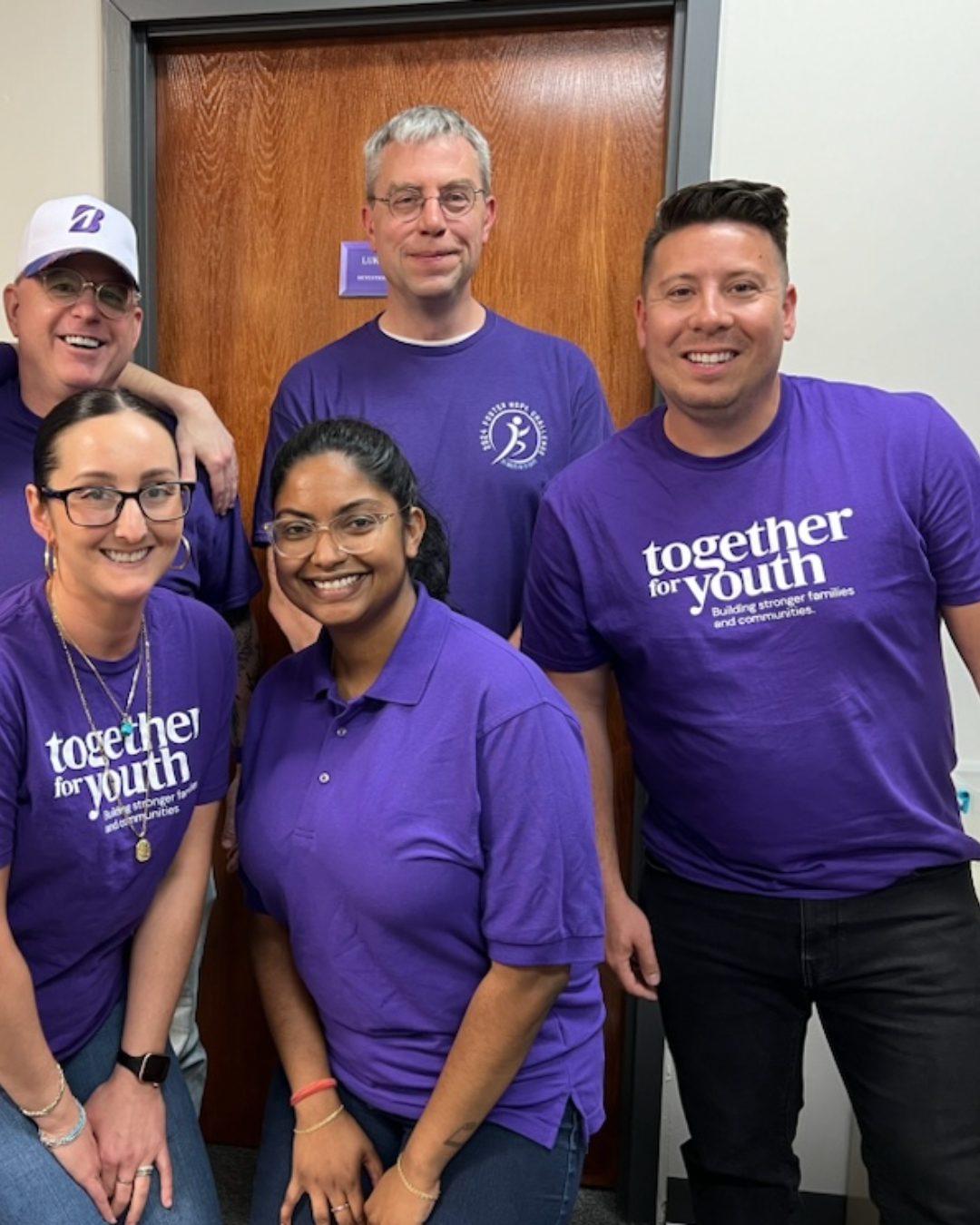 Five people wearing purple shirts with the text 
